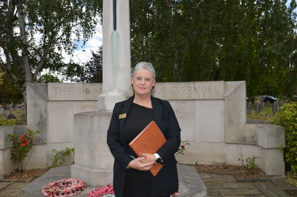 Dawn holding her ceremony folder beside a memorial